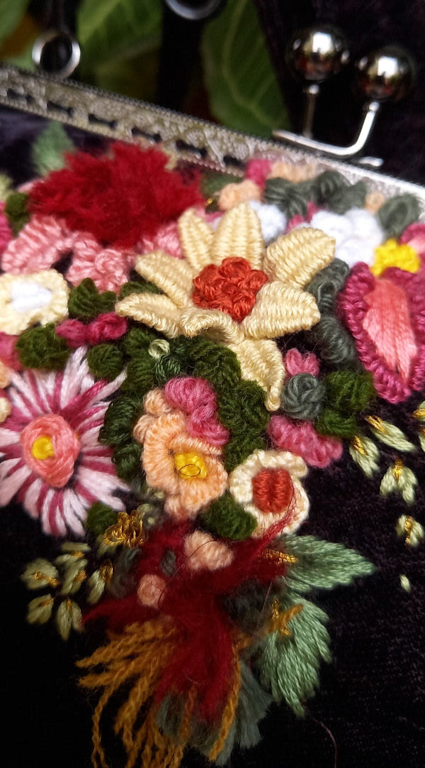A sleek velvet purse with vintage look decorated with hand embroidered beautiful flowers, combining elegance and fun in one stylish piece.