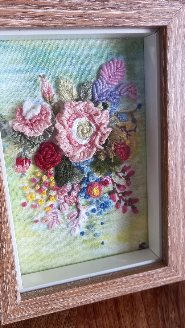 Bunch of hand embroidered 3d flowers in pastel colors and mounted in a frame with wooden finish