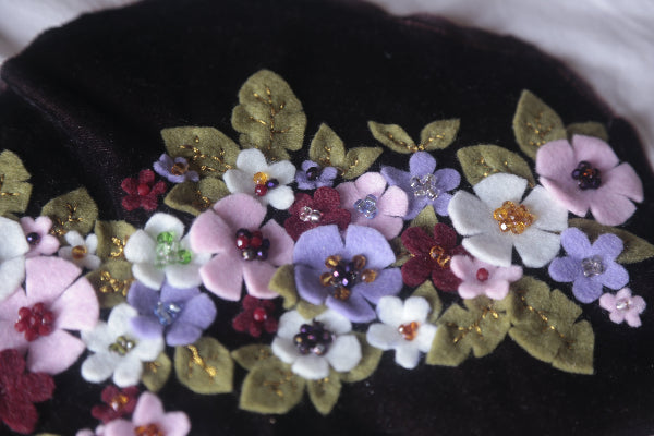 A trendy black handbag decorated with vibrant flowers in Pastel Colors, ideal for sprucing up your look with a touch of flair.