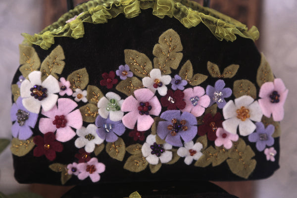 A trendy velvet purse embellished with beautiful flowers, making it a delightful addition to your accessory collection