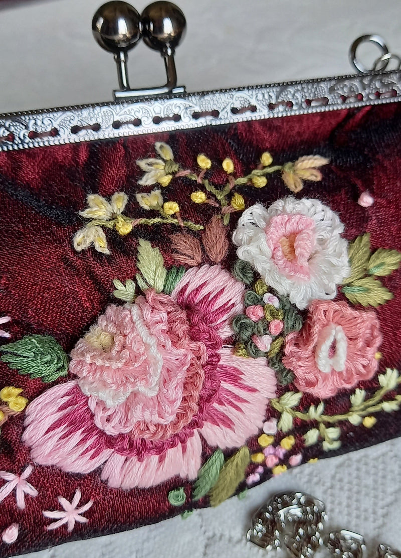 Close up of velvet handcrafted purse with hand embroidered serene pastel peach flowers 