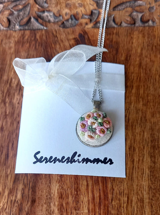 Delicate pastel colors hand embroidery flowers on a pendant