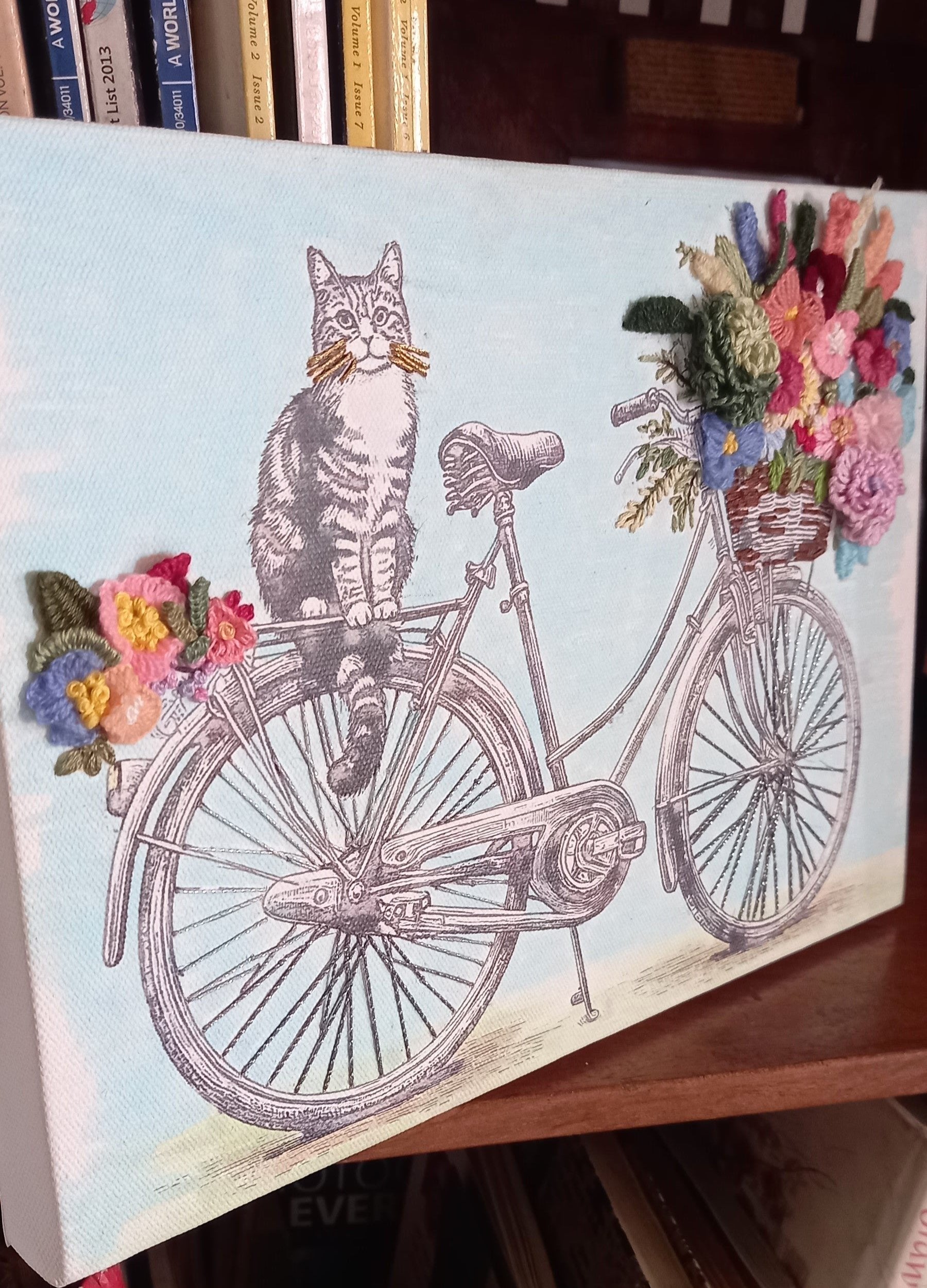 Canvas with a printed black and white cat sitting on a cycle with a hand embroidered bouquet of flowers