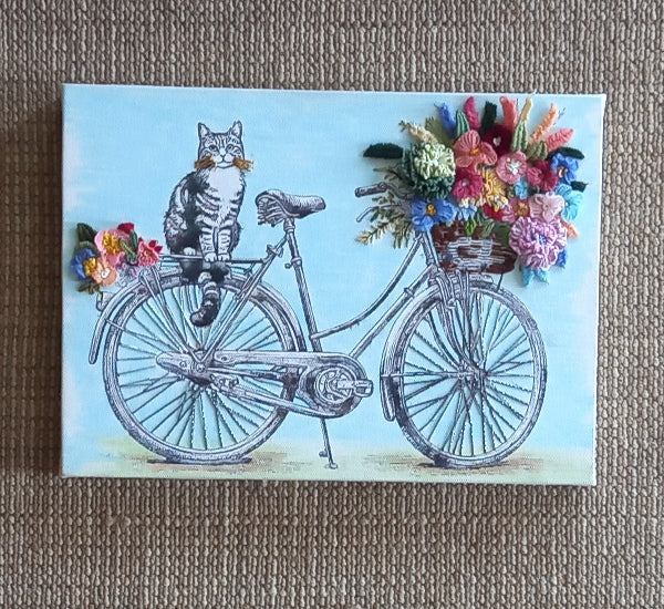 Canvas with a printed black and white cat sitting on a cycle with a hand embroidered bouquet of flowers