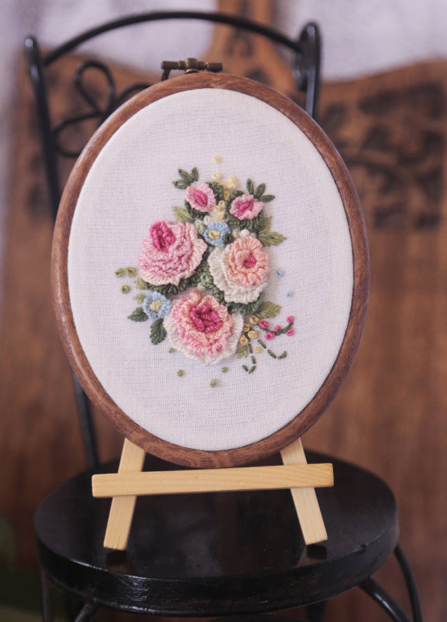 Delicate artistic embroidery showing three charming pastel peach roses centered on a hoop frame