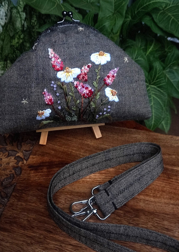 A handcrafted linen purse with cotton lining, adorned with delicate hand-embroidered wildflowers, showcasing intricate stitching and craftsmanship