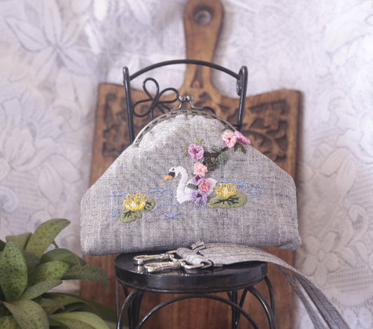 Linen purse with hand embroidered swan and flowers, showcasing intricate craft, cotton lining inside.