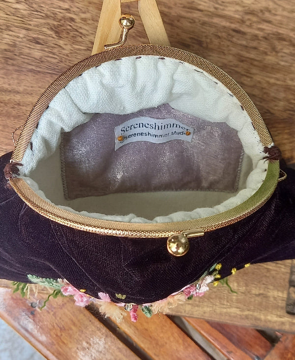 Beautifully crafted velvet purse adorned with hand-embroidered floral and leaf designs, exuding a lovely vintage appeal.