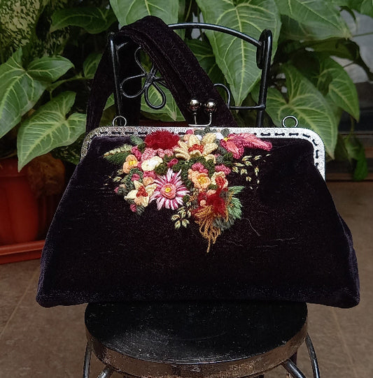 An elegant velvet purse with hand embroidered floral designs, reflecting a harmonious blend of style and artistic flair.