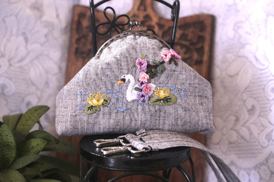 Elegant linen purse adorned with hand embroidered swan and floral patterns, complete with a cotton lining.