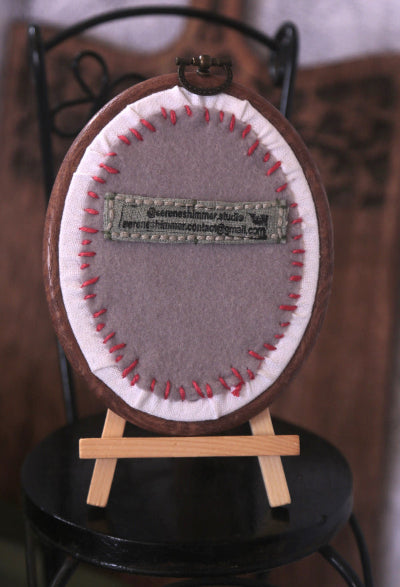Charming embroidery hoop art with peach and blue flowers, rose buds, and green leaves, creating a lovely floral display.