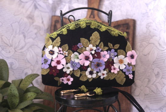 A stylish handcrafted velvet purse adorned with colorful flowers, perfect for adding a touch of elegance to any outfit.