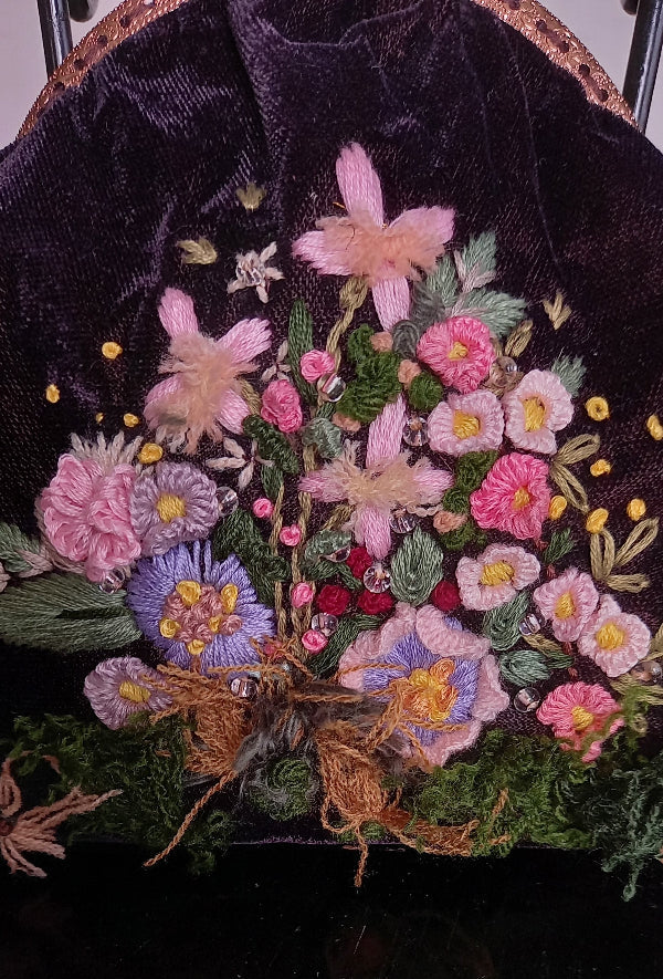 Elegant, handcrafted velvet purse adorned with hand-embroidered flowers and leaves, capturing a charming vintage aesthetic.